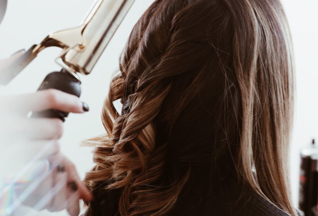 Frisør krøller håret til kunde med krølltang.